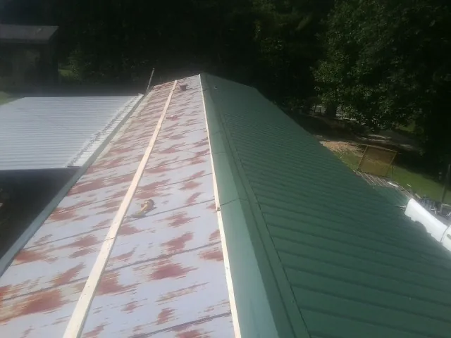 Old rusted panels beside newly installed green metal roofing — Wind Damage Roof Repair by Roofing Brothers in Hollywood